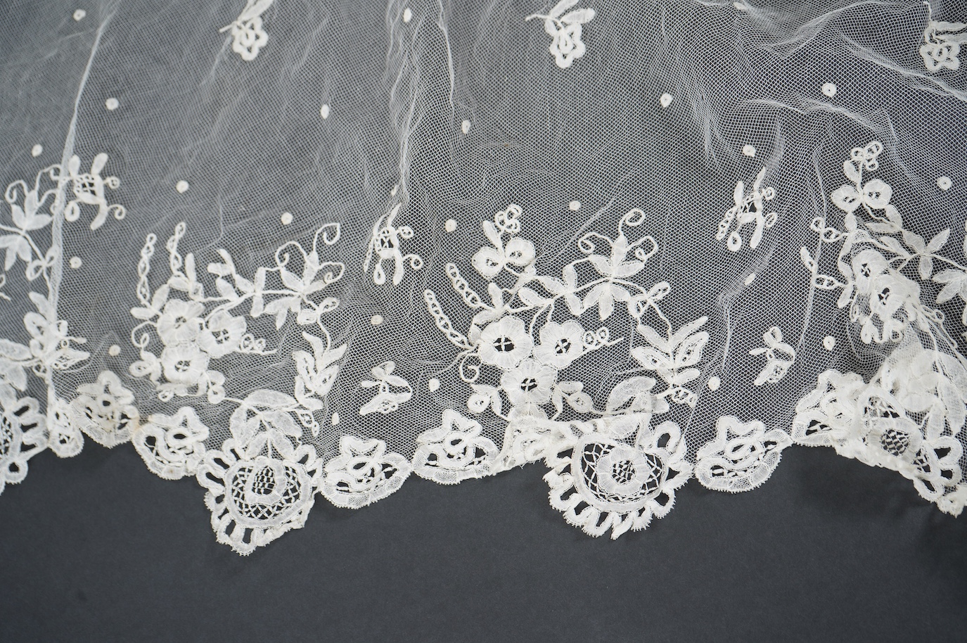 A late Edwardian hand bobbin lace Honiton and net wedding veil, approximately 248cm x 230cm. Condition - one corner has corner has been attached to a hair comb and damaged the netting.